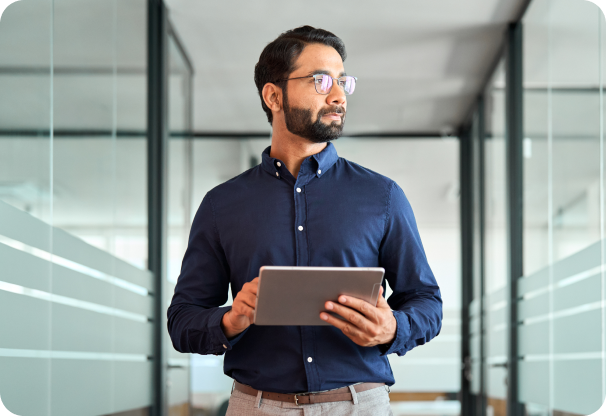 Guy with glasses holding laptop walking in an office hallway